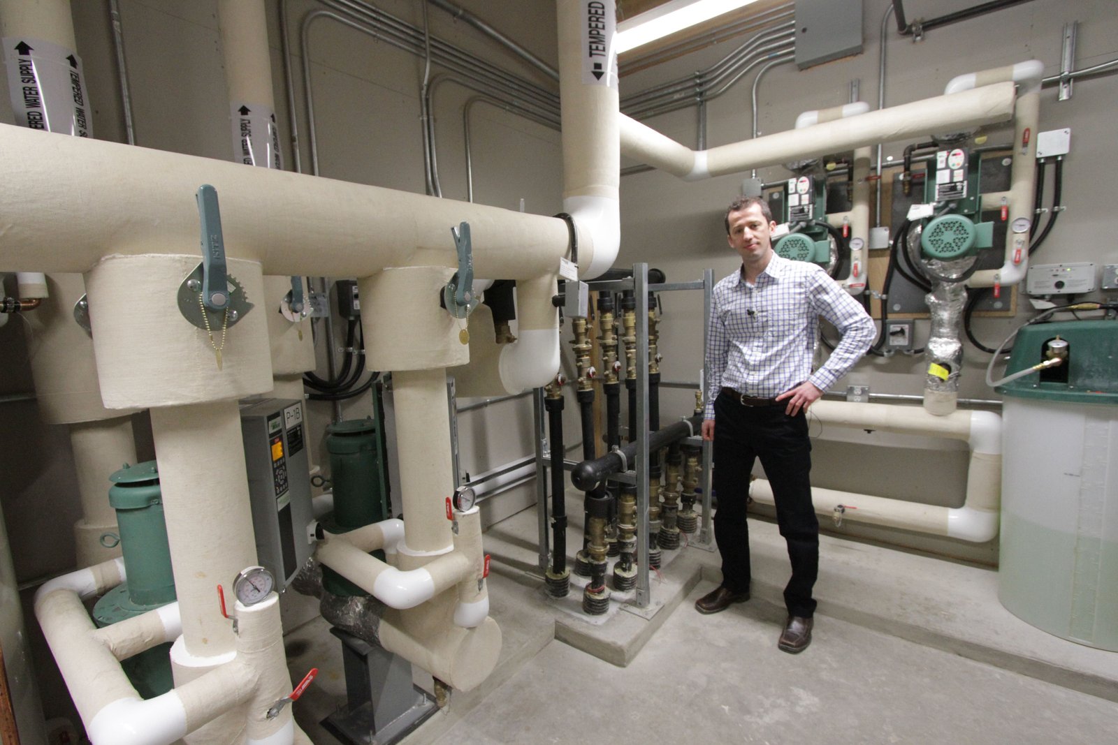 Jacob Komar of Revolve Engineering shows off the workings of the geothermal system in the net-zero Mosaic Centre commercial building. Photo David Dodge, Green Energy Futures