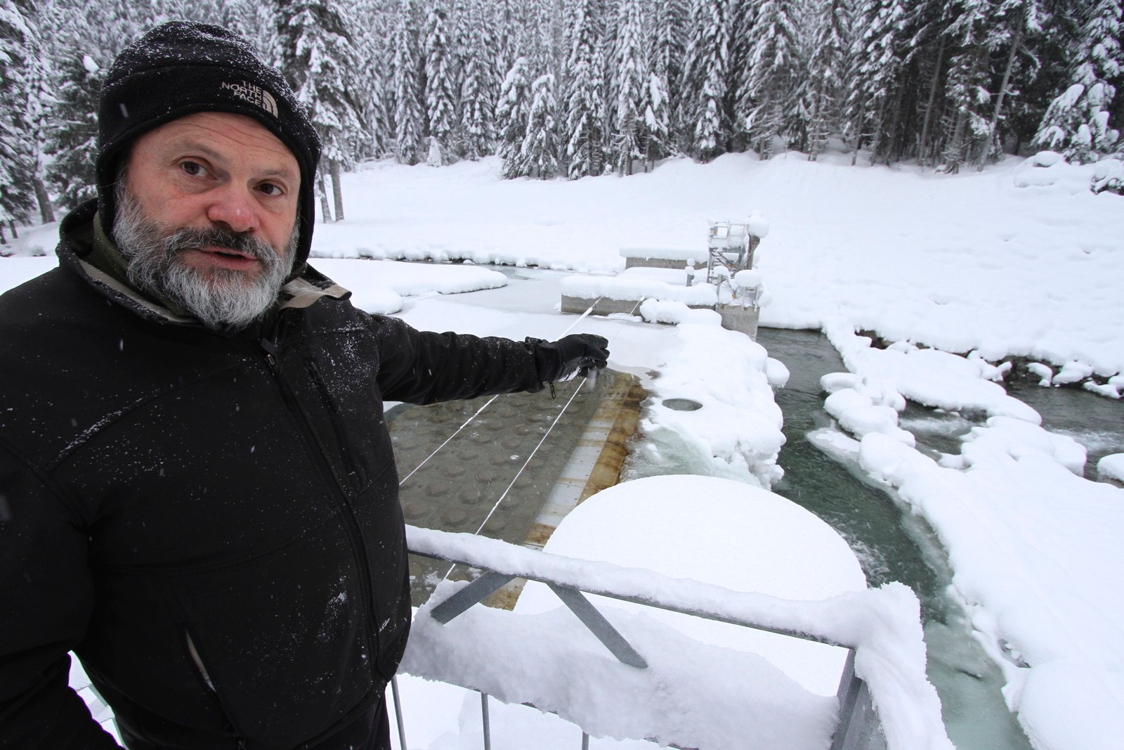 Don Gamache, operator of the Fitzsimmons Creek run-of-river project, gestures at the weir where water is diverted into a penstock pipe that travels 3.5 km down to the power plant. This headpond is sandwhiched between Whistler and Blackcomb mountains. Photo David Dodge